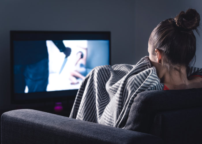 Woman watching scary movie on screen