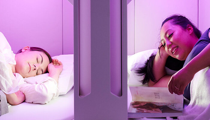 People resting in Sky Nest, lay-flat economy seats on Air New Zealand that resemble bunk beds