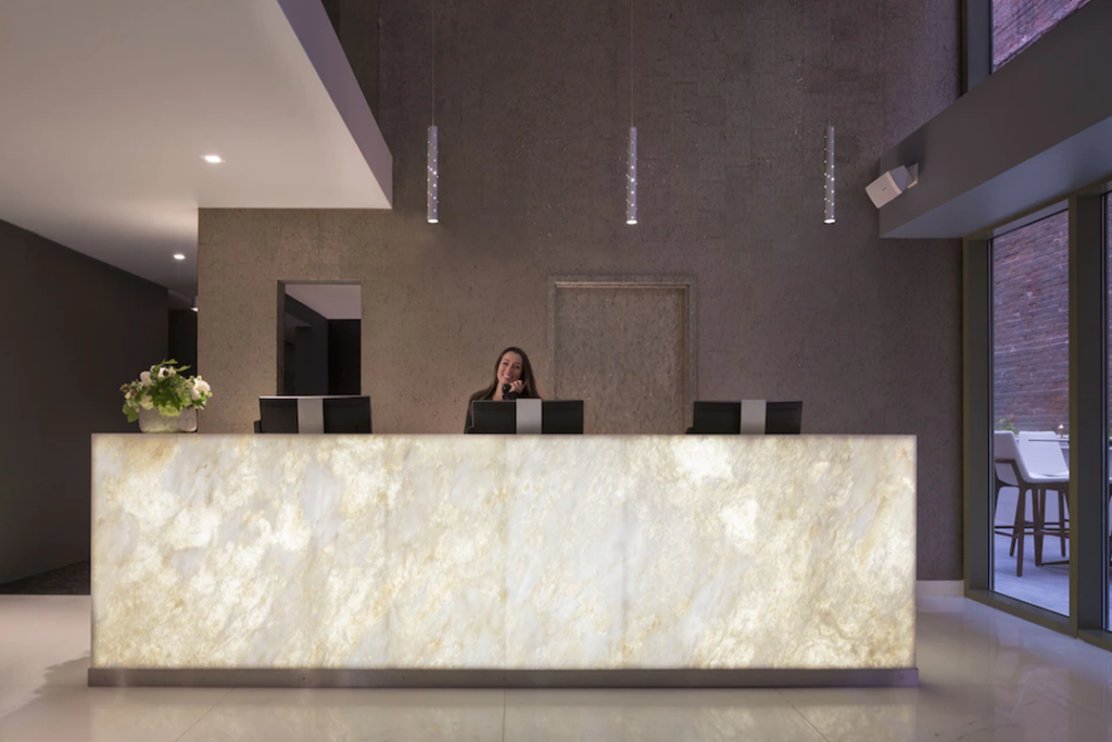 Hotel VIA's reception desk with agent on the phone and smiling