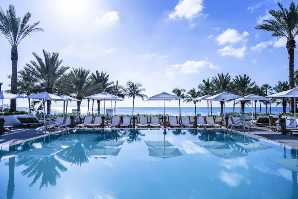 View of the pool at the Nobu Hotel Miami Beach with palm trees and the ocean in the distance